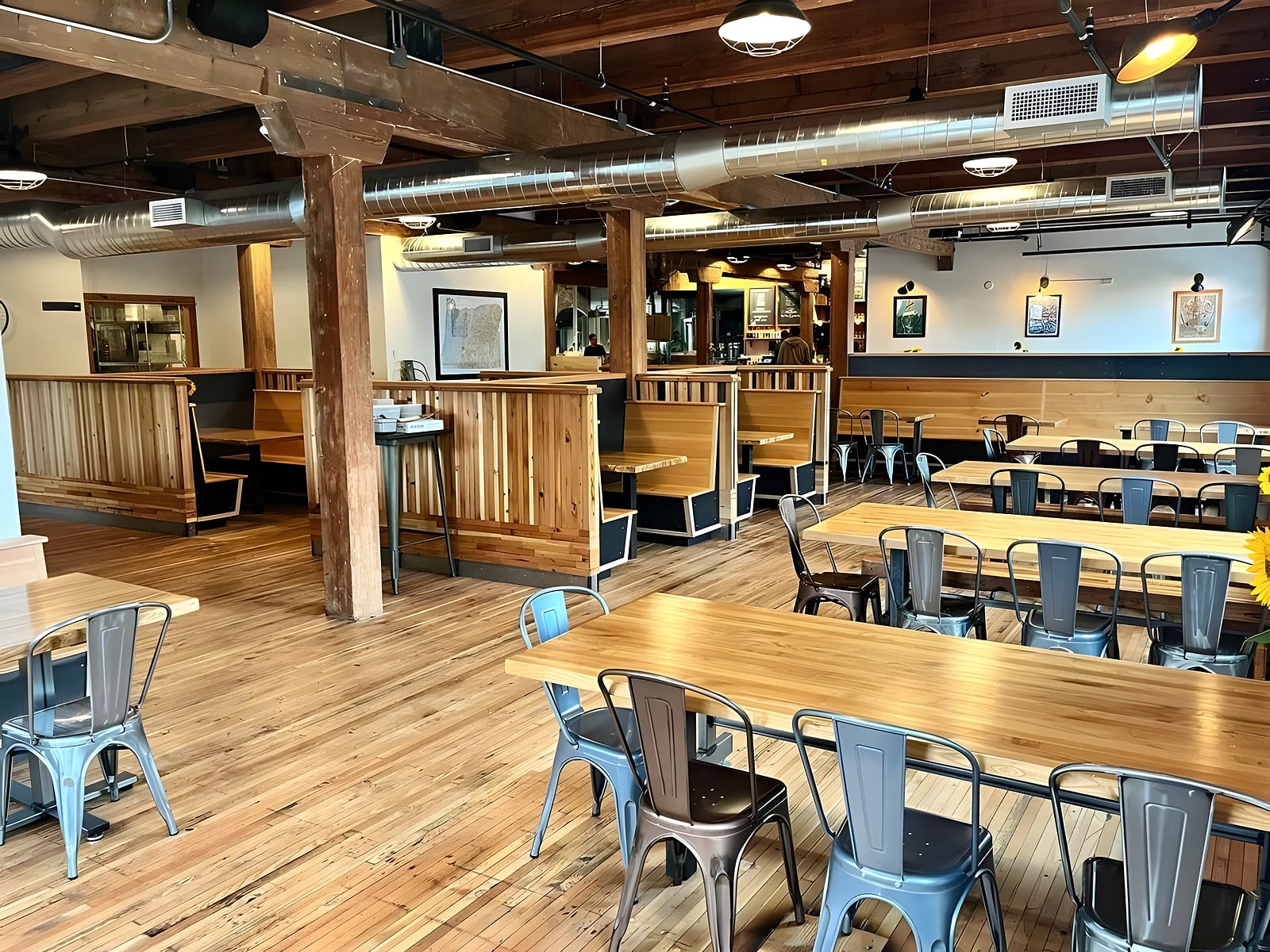 The dining room: wooden booths, long tables and metal chairs under an exposed timber ceiling
